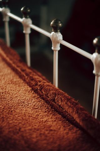 Bottom of a bed with metal bars and a cozy blanket