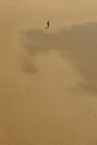 A person walking on a deserted beach where multiple footsteps can be seen