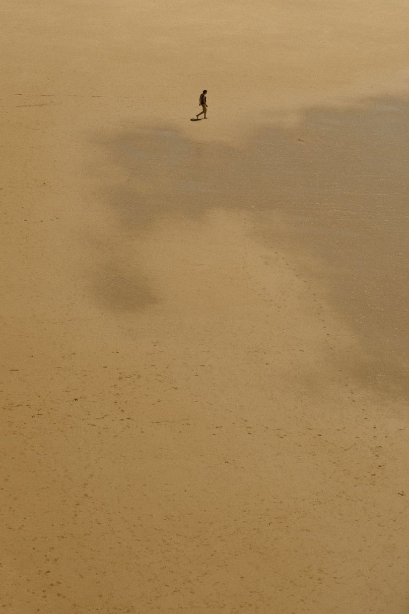 A person walking on a deserted beach where multiple footsteps can be seen