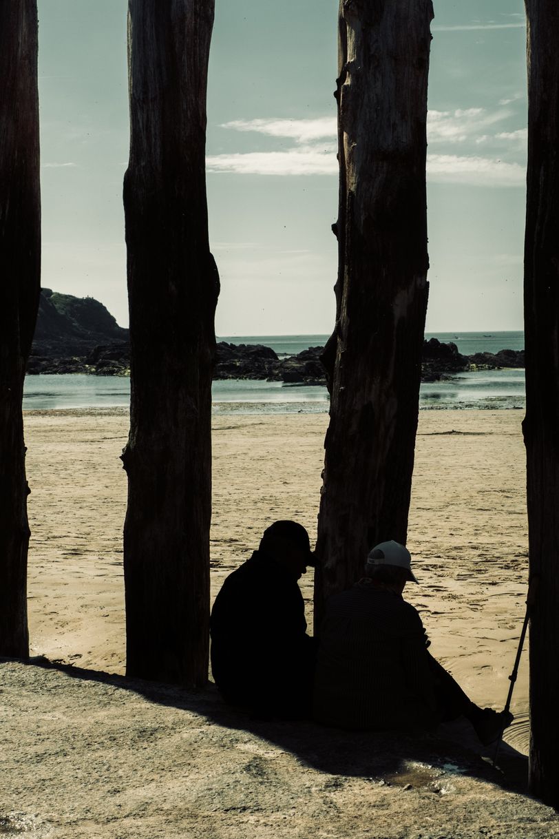 A couple resting near breakwater poles