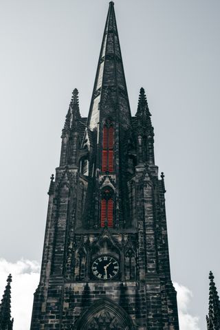 Bell tower of a church made of black stone and shutters painted in red