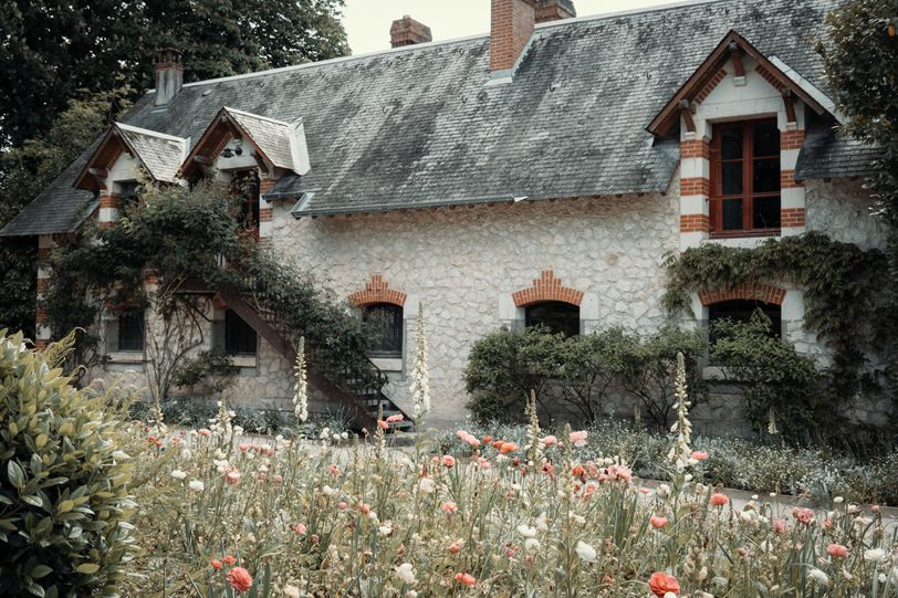 Stone house covered and surrounded with blooming flora