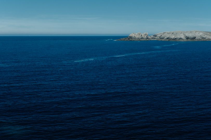 A dark blue sea cut by rocky shores