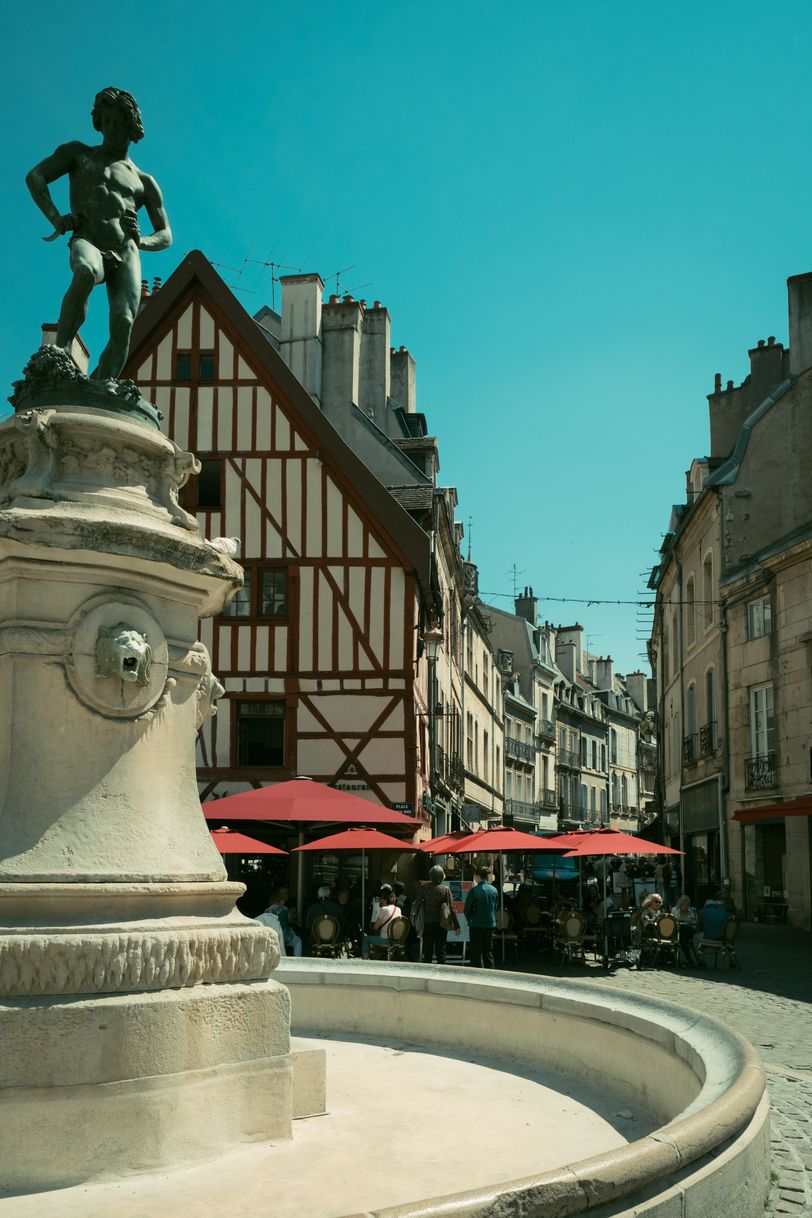 An empty fountain in the streets with a statue of an ephebe on top