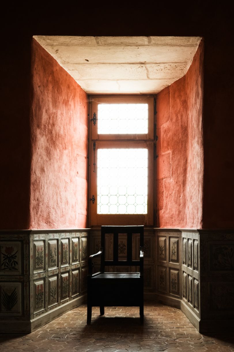 A wooden chair in a lit corner of a room