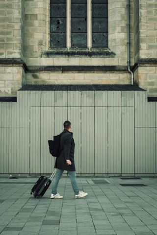 A traveller passing by a church under restoration with broken stained glass