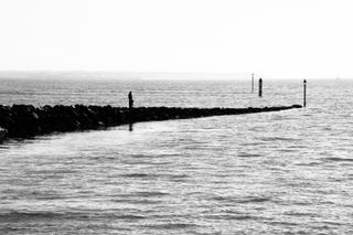Black and white picture of a dad and his child fishing from a stone pier