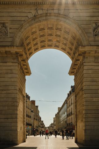 Sturdy arch at the beginning of a pedestrian street on a sunny day with people walking around