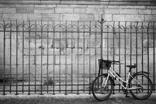 A bicycle placed on a fence with a wall behind