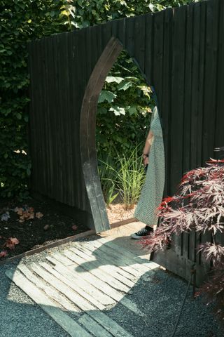 Shadow of someone going through a gate of a palisade in a garden