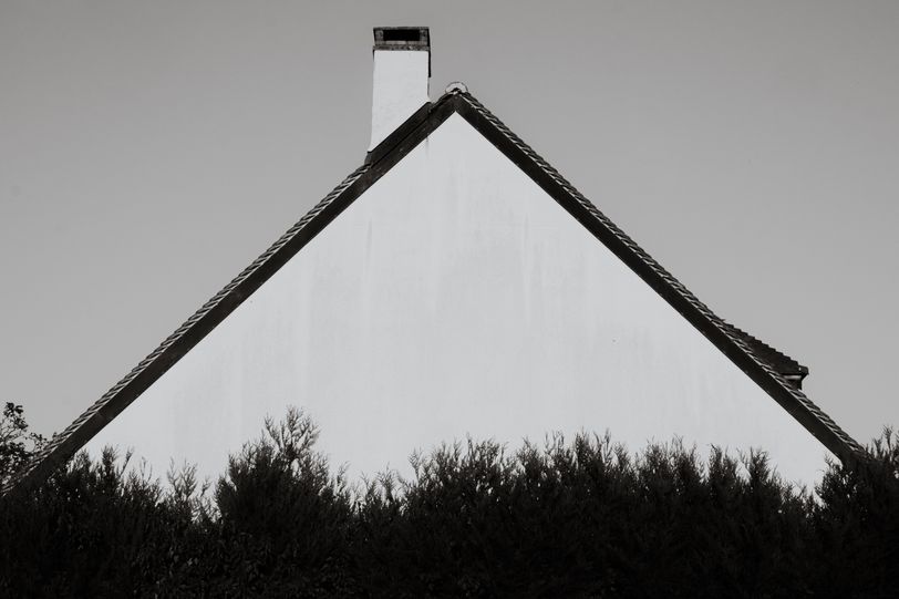 Triangular side of a house behind a row of trees