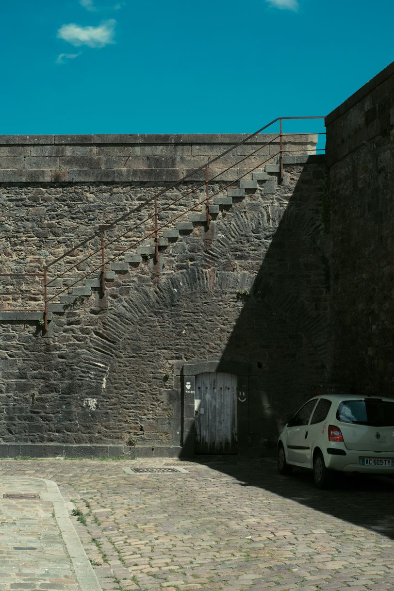 A car parked in the shadow of tall rampart