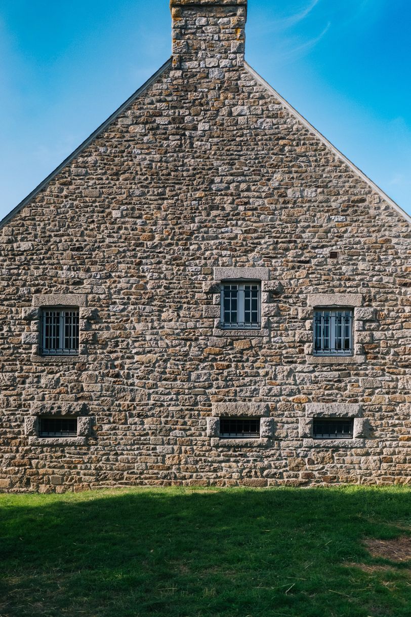 Stone house with a few small windows before a green lawn