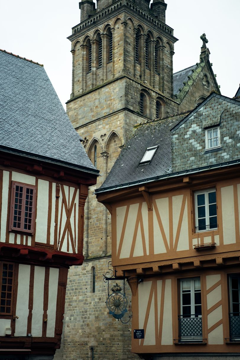 Two half-timbered houses before a tall stone church