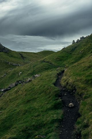 Green path in the mountains under a threatening stormy sky