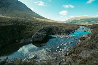 A water stream going down from a mountain to a green valley