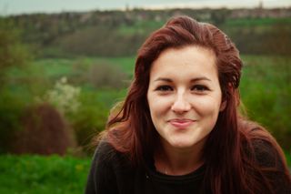 A young woman smiling at the camera in embarrassed way