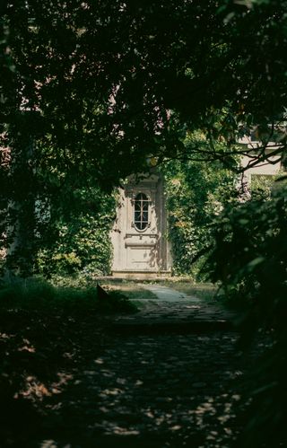 A shadowy tunnel leading to a white door in the sun