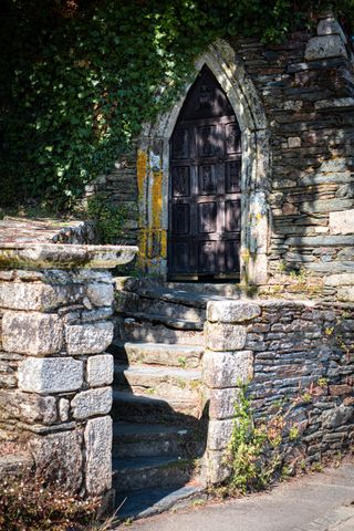 An ancient door made of wood before small stone stairs