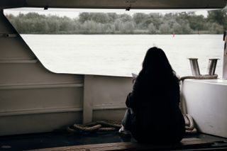 A woman sitting on a deck of a boat watching the landscape during the trip