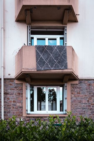 Picture of the balconies of a building with a rug drying up on one of them