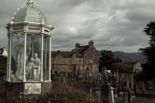 Cemetery with an ostentatious tomb in the foreground and sober tombstones in the background