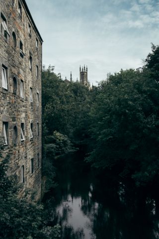 A river passing by an old building before fading into the woods