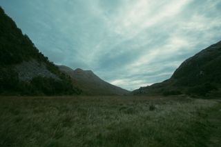 A green valley between mountains with nothing but grass everywhere