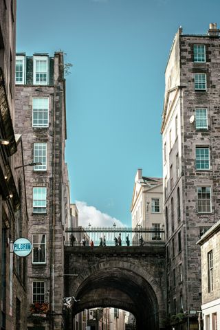 People walking over a bridge going behind two buildings