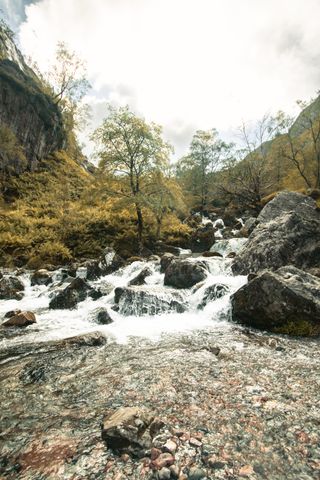 Source of water going down from a hill through rocks in autumn