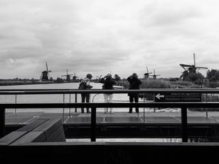 3 phototographers on a pontoon takings pictures of a river between windmill in Netherlands