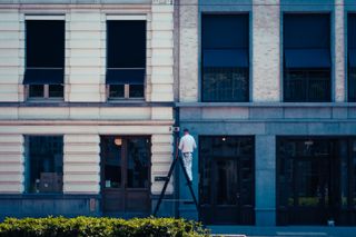 View of a street with a worker mount on a ladder repairing a building