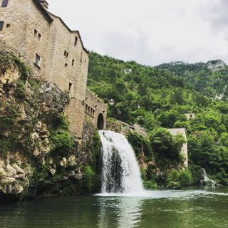 A village with a stream ending into a waterfall to the river