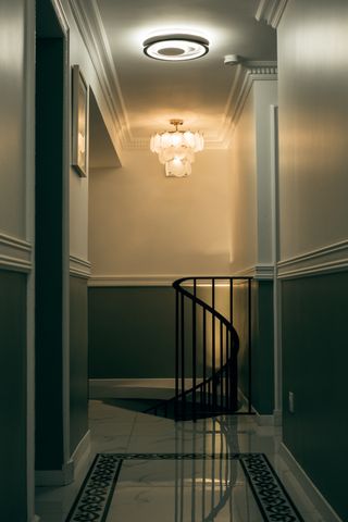 Long corridor between rooms and a spiral staircase going down at its end