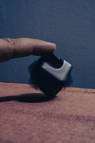 A finger holding straight a rotating fidget on a table