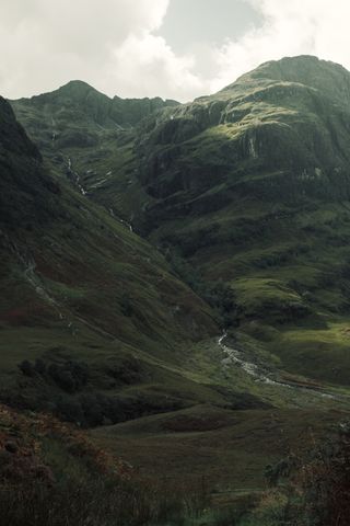 View to a water stream going down from the top of a mountain to the bottom of the valley