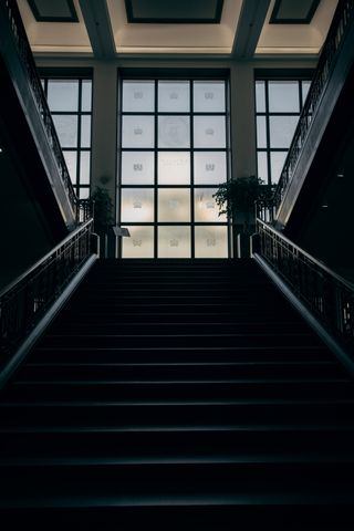 Stairway in the dark with a big window at the top. Symmetry and lines everywhere in the picture