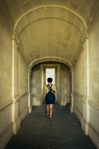 A woman going towards a window at the end of a narrowing corridor