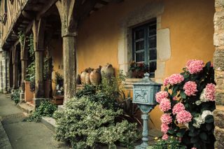 Cozy and colorful front house with flowers and pottery under a wooden porch