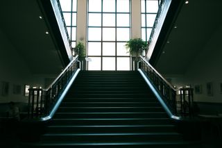 Stairway starting in the dark and leading to a very light bay window