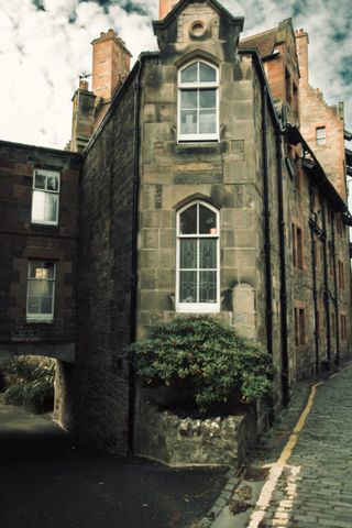 Old british corner house in a small village between two crossing road with a small angle.