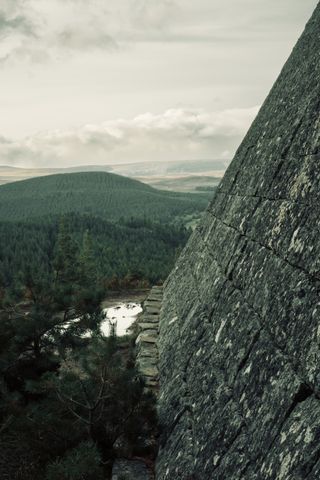 Base of a pyramid made of stone on the top of a hill with a valley in the background.