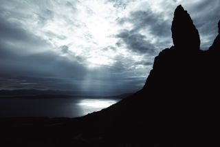 Backlight landscape of a loch from a hill with the raising sun coming through clouds