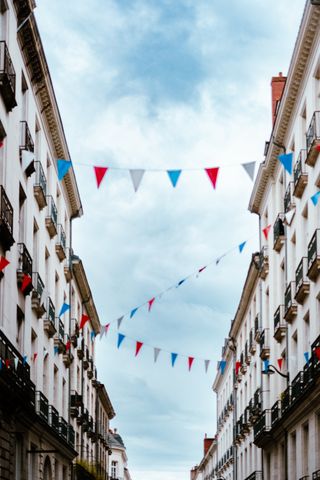 Low angle of a street between old buildings connected to each other with colored pennants