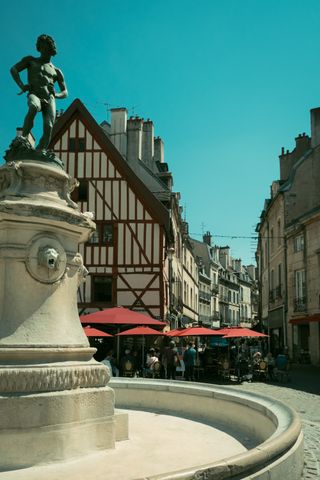 An empty fountain in the streets with a statue of an ephebe on top