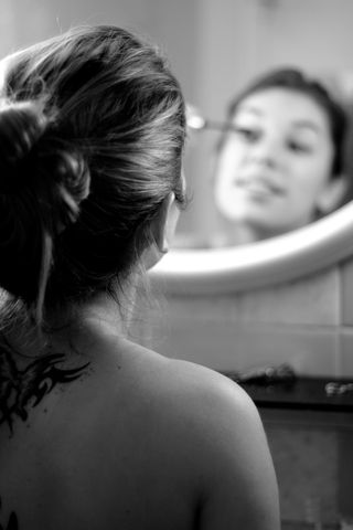 Portrait through a mirror of a woman doing her make up