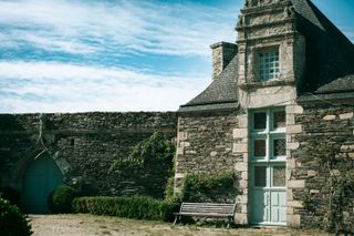 An old annex house on a landlord domain next to a wall with nothing visible behind it except a blue sky