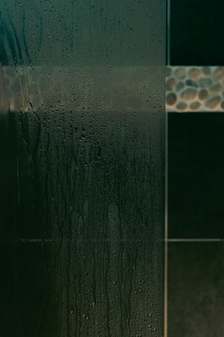 Wall tiles of a bathroom behind a wet glass