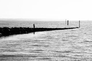 Black and white picture of a dad and his child fishing from a stone pier