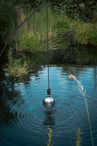 Sculpture hanging above the water making waves